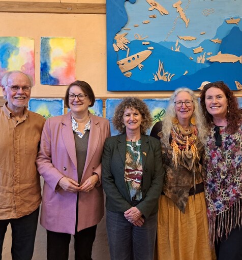 Community leaders and Kindlehill staff gather before student art, honouring the new school entrance and vibrant village spirit.