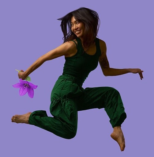 A joyous performer leaps mid-air with a flower, celebrating the physical energy and imaginative magic of live storytelling.